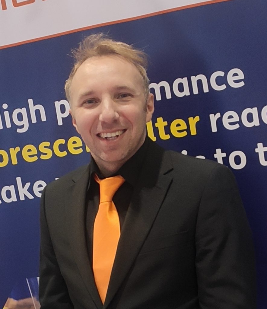 Karl Obszanski in a black suit with orange tie