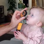 Infant receiving a gentle pediatric eye exam with the Lumio device under white light by Aston Vision Science