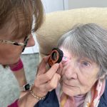 Older woman undergoing an eye exam using the handheld Lumio device by Aston Vision Sciences