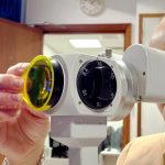 Clinician using a slit lamp with aston vision sciences' fluorescent filter attached to front objective lens