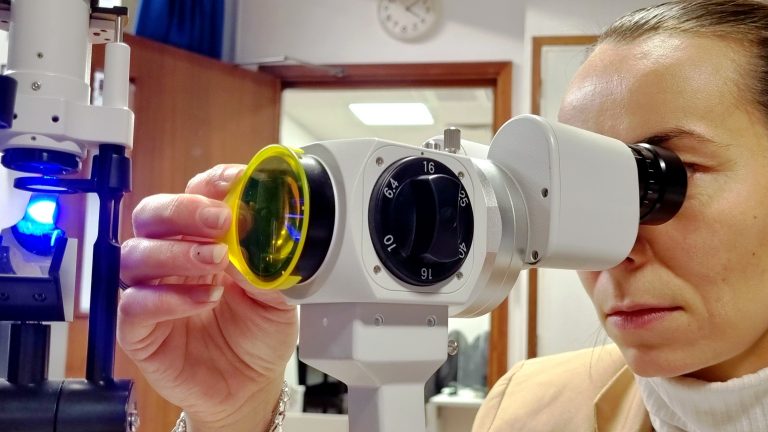 Clinician using a slit lamp with aston vision sciences' fluorescent filter attached to front objective lens