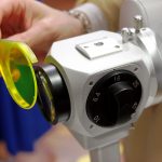 Person placing a yellow fluorescein filter onto a slit lamp in preparation for a dy eye examination