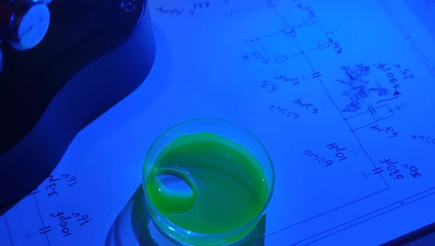 Illuminated Fluorescein under blue light Liquid container holding fluorescein that is excited using blue light to make it glow green.